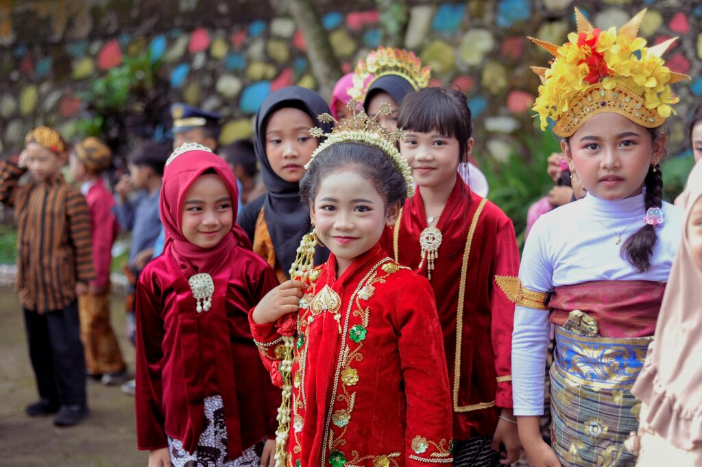 Group of children in traditional attire celebrating a colorful cultural festival outdoors.