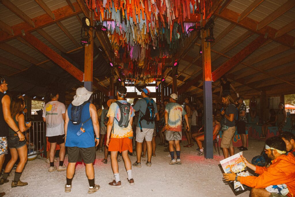 Lively crowd enjoying a colorful indoor festival adorned with vibrant decorations and tie-dye outfits.