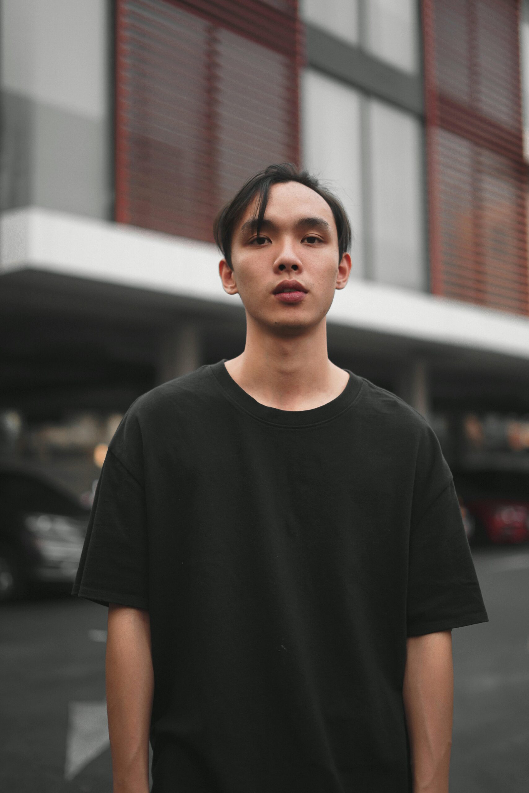 A young man in casual attire stands confidently in an urban outdoor environment.